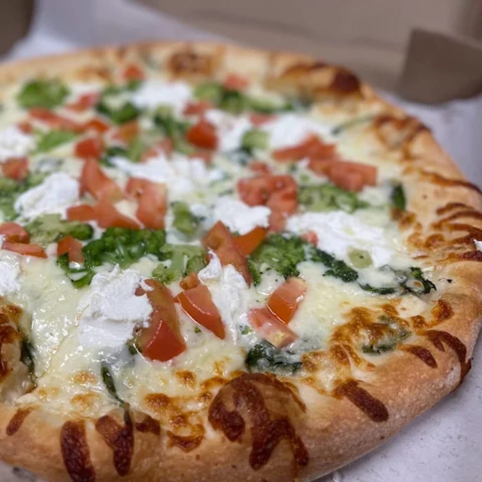 Speedy's Pizza white pizza with broccoli, diced tomatoes, and dollops of ricotta cheese.